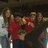 A pixelated static image shows a person in red clothing holding an object, with other figures partially visible against a dark background.
