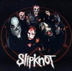 Static image of a band logo featuring stylized faces within an oval frame and bold text below, set against a dark background with red circular accents.