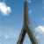 Pixelated image of a tall dark structure against a blue sky with white clouds, viewed from a low angle.