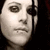 Pixelated grayscale close-up of a human face with visible facial features and dark background.