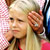 Static pixelated image of a person with light-colored hair and partial facial features, set against a pink checkered background on the left side.