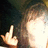A person with long brown hair makes a middle finger gesture with their right hand against a dark background.