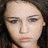 Static pixelated image of a person's face with light skin tone, dark hair visible on the sides, and neutral expression.