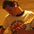 A pixelated image of a person in a light-colored shirt with dark collar, holding an object against a warm-toned background.