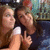Two people in a close-up pose with one person making a middle finger gesture, set against an indistinct background.
