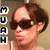 Pixelated image of a person with brown hair wearing dark sunglasses, standing beside vertical black-and-white text blocks on the left.