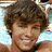 Pixelated image of a person with brown curly hair smiling, next to purple text blocks and pink heart symbols on white background.