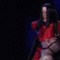 A person in a red sleeveless top and black arm sleeves performs a sequence of movements against a dark blue curtain background.