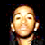 Pixelated static image of a person's face with closed eyes and visible ear, set against dark background with colored pixel artifacts.