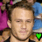 Pixelated image of two identical male figures with short brown hair, wearing black shirts, with green 'RIP' text and a green heart symbol above them.