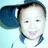 A child wearing a dark blue cap and light blue shirt with dark blue collar, smiling with mouth open, against light blue background.