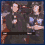 Pixelated animation of two figures in dark clothing with light blue accents, one figure holding a white object while the other shifts pose; adjacent displays "WATCH OUT" text