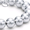 A close-up of a string of large, reflective silver beads arranged in a curved pattern on a white background.