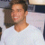 Static pixelated image of a person in a white shirt against a light background with dark elements on the sides.