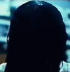 A sequence of showing a dark-haired figure with long hair, transitioning from back view to front view revealing a pale face and white clothing against a blurred background