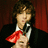 A pixelated image of a person in formal attire with red bow tie against dark red curtains, featuring overlaid text and an animated heart symbol.