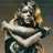 A pixelated figure with blonde hair and a dark outfit, arms crossed in front of the chest against a muted background.