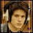 A person wearing over-ear headphones with a brown background and vertical colored bars on the left side.