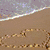 Beach scene with wave, sand drawing of heart and chain; hands forming heart shape over blue background; pixelated heart collage.