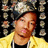Pixelated static image of a person with reddish-brown hair wearing a yellow jacket over dark clothing, set against a black background with blurred pixel clusters.