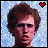 Pixelated portrait of a person with brown curly hair against light blue background, two heart icons above head showing red filled and white outlined states.