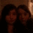 Two women pose together in a dark setting with warm lighting, overlaid with pixelated text and symbols in cyan and pink.