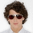 Pixelated portrait of a person with short brown hair, dark red sunglasses, and light skin tone against white background.