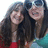 Two people with long dark hair smiling, one in red top, one in teal top, next to pixelated text on white background.