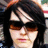 Pixelated portrait of a person with dark hair and sunglasses on the left, red text reading 'i think i' above 'too much love you' on black background.