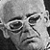 Black-and-white pixelated icon showing a stylized face with exaggerated features including large eyes, thick eyebrows, and a prominent nose on a gray background.