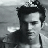 Black-and-white pixelated image of a person with dark hair styled upward, positioned left of center against a light background.