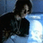 Pixelated image of a person with dark hair in a dimly lit setting, overlaid with green pixelated text on a black background.