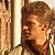 Pixelated static image of a person's face and upper body in profile view with brown hair, visible ear, and partial shoulder against a light background.