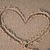 Three heart-shaped outlines drawn in light brown sand on a beige background, with the rightmost heart partially cropped.
