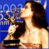 Woman holding golden Emmy award against blue background with '2003' and '55th' text, wearing strapless dress, with text overlays appearing sequentially.