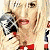 A 4-frame animated contact sheet showing a woman with blonde hair holding a microphone, wearing a red bow tie and white top with blue accents, in sequential poses against a gray background.