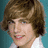 Pixelated image of a person with brown hair and a white shirt on a teal background, with pixelated text and emoticons arranged around the edges.
