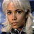Pixelated static image of a person with light-colored hair wearing dark clothing and a white collar, set against a blurred background.
