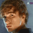 Pixelated close-up of a person with brown hair and light skin, wearing a dark top against a blue background.