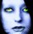 Pixelated close-up of a face with pale blue skin, yellow-green eyes, and dark lips against a black background.