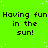 Bright green background with repeated black text "Having fun in the sun!" and scattered white dots, partially cropped on the right.