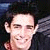A split-screen image shows two versions of a person with dark hair, one smiling broadly and the other with a neutral expression, next to cyan text reading "He's taking me over" on a dark background.