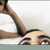 Pixelated image of a person with dark hair wearing a white shirt, lying down and holding an object near their face.