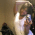 A pixelated image shows a person with dark hair holding a small device near their face against a muted brown background.