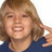 Pixelated close-up of a person with light brown hair wearing a dark blue top, smiling broadly against a white background.