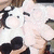 Pixelated image of a person with dark hair and light skin, wearing a white top, holding an object near their face.