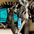 A pixelated image of a mechanical or robotic figure with glowing cyan elements against a brown and black background.