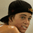 A pixelated image of a person wearing a black cap with a small red and yellow emblem, positioned on the left side of a blue background.