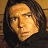 Pixelated close-up of a person's face with light skin tone, dark hair, and neutral expression against a brown background.