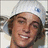 A pixelated image of a person with brown hair wearing a white head covering, smiling in two side-by-side frames.